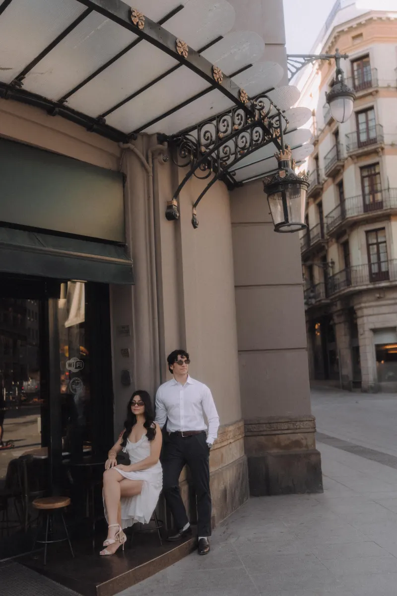 Stylish couple enjoys a relaxed moment outside a café in Barcelona during their couples & engagements photoshoot.