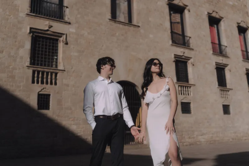 Stylish couple holding hands in sunlight, sharing a relaxed moment during a couples & engagements photoshoot in the city.