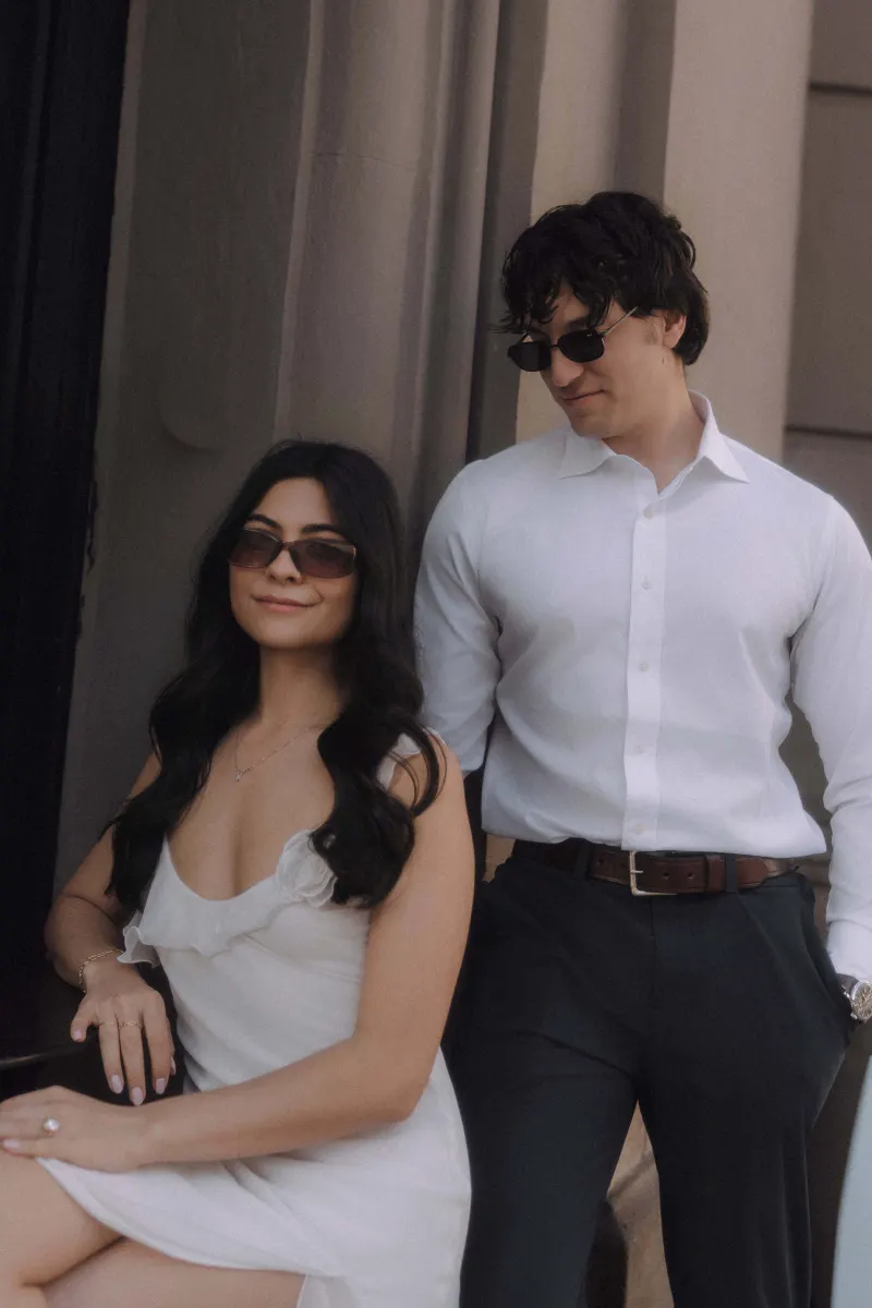 Stylish couple in sunglasses share a relaxed, confident moment during a couples & engagements photoshoot in the city.