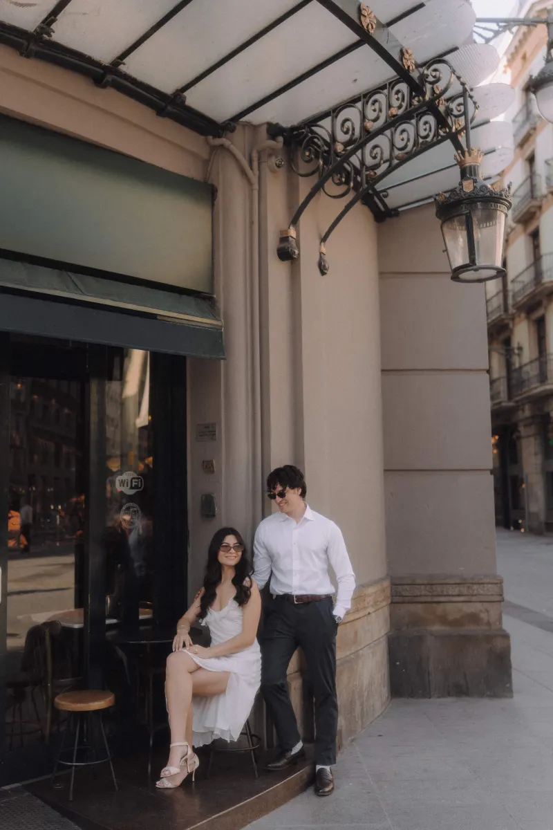 Stylish couple shares a relaxed moment outside a café during their couples & engagements photoshoot in the city.