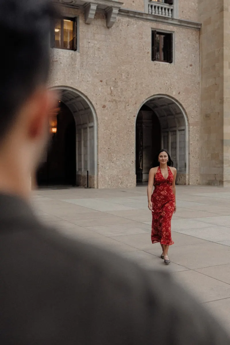 Sydney walks toward Dan across the courtyard in a cinematic Montserrat engagement photograph.