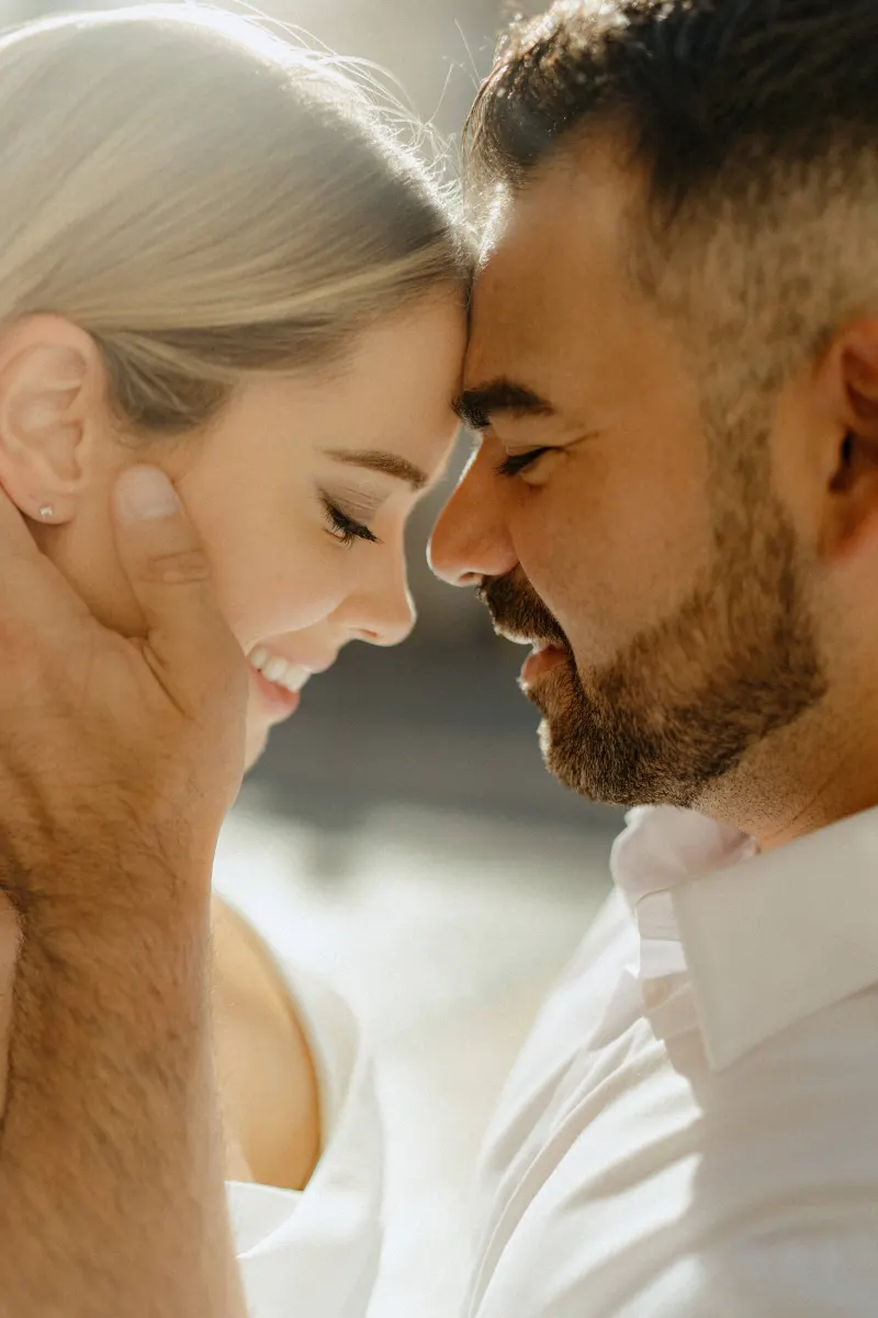 Tender moment as a couple in white share a gentle forehead touch during their couples & engagements photoshoot.