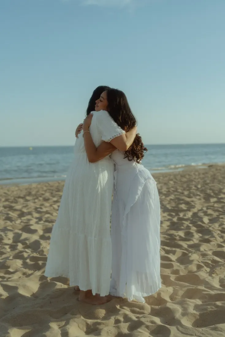 The newly engaged couple share a quiet embrace on Castelldefels Beach in evening light.