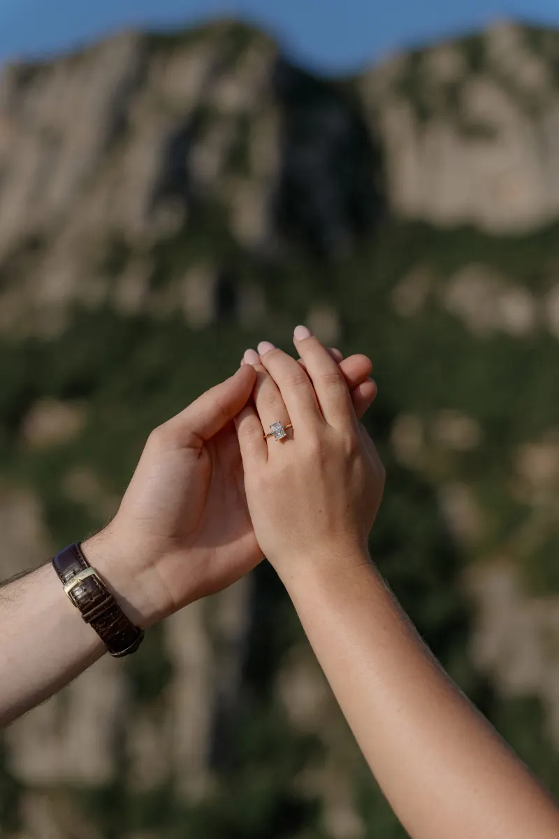 Tim and Megan raise their joined hands in front of Montserrat's cliffs.