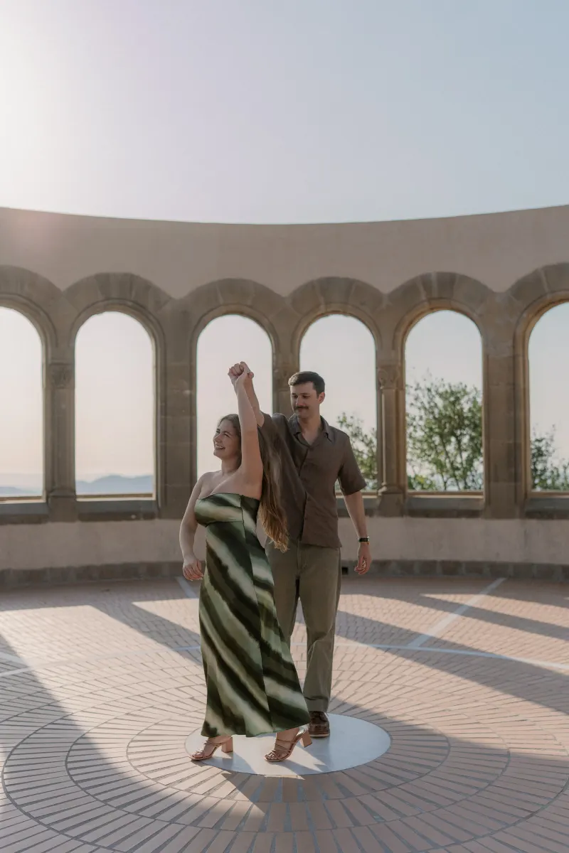 Tim and Megan raise their joined hands in the semicircular stone gallery.