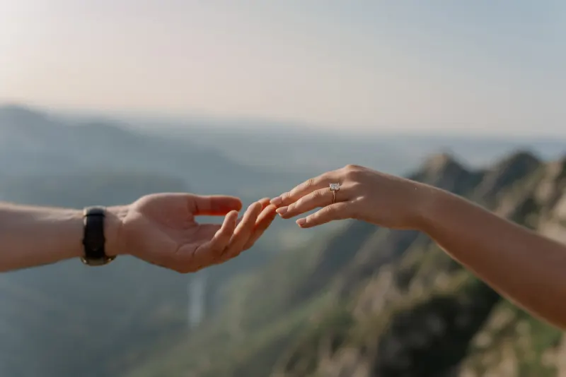Tim and Megan reach towards each other with the valley beyond their hands.
