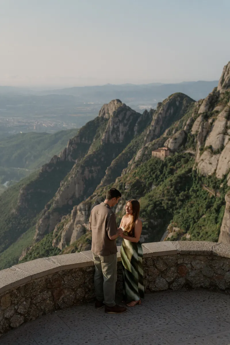 Tim and Megan stand together beside the curved stone parapet above the valley.
