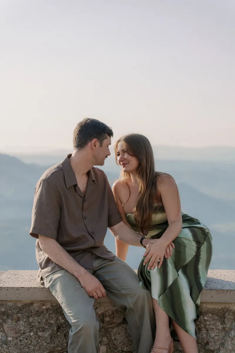 Tim and Megan turn towards each other while seated above the valley.
