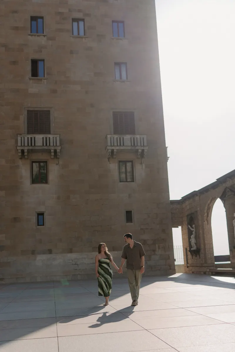 Tim and Megan walk hand in hand across the open monastery courtyard.