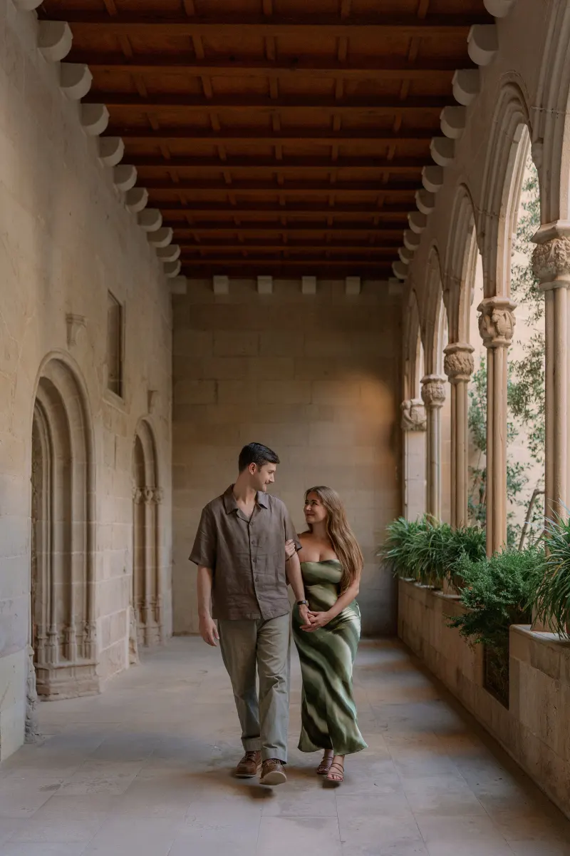 Tim and Megan walk together through a covered stone arcade.