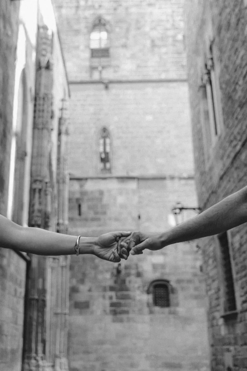 Two people gently holding hands in a romantic moment during a couples & engagements photoshoot in a historic city alley.