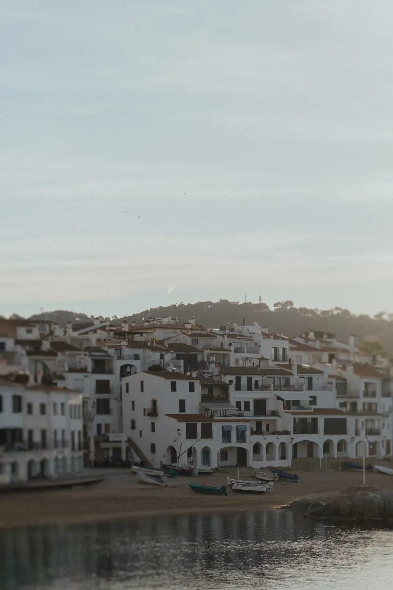 Whitewashed seaside houses and small boats line the tranquil shore, perfect for a surprise proposal photoshoot in Spain.