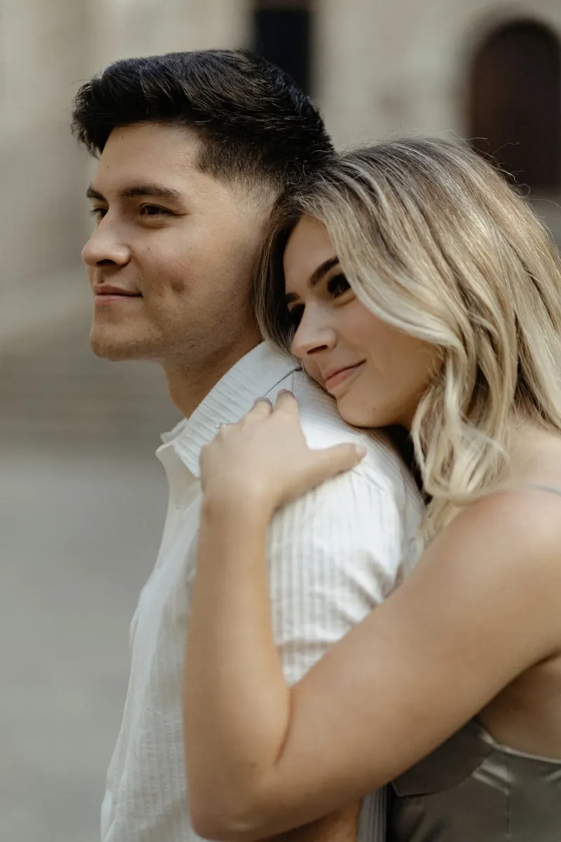 Woman embraces her partner from behind, both smiling softly during a Vacation Portraits session in Barcelona.