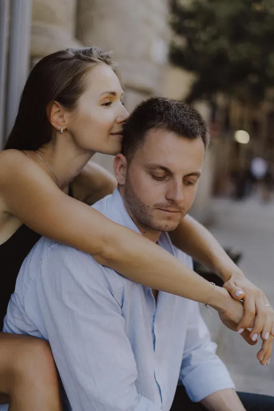 Woman embraces her partner from behind, sharing a quiet, loving moment during a couples & engagements photoshoot outdoors.