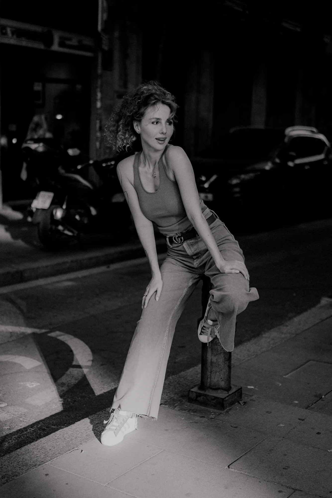 Woman enjoys a playful pose on a city sidewalk during a Vacation Portraits photoshoot, capturing a carefree moment.