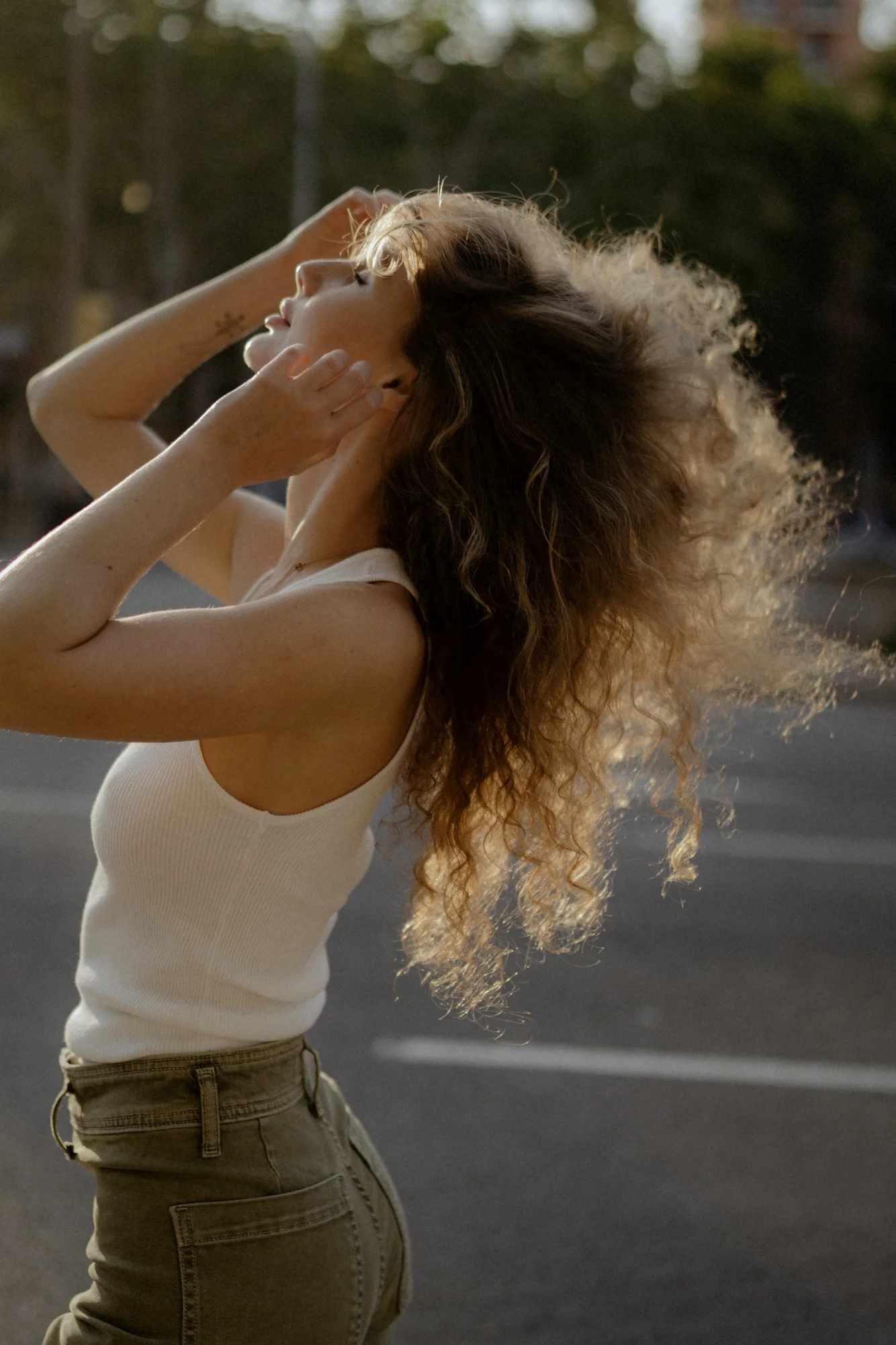 Woman enjoys golden hour light on a city street, her hair catching the sun during a Vacation Portraits photoshoot.