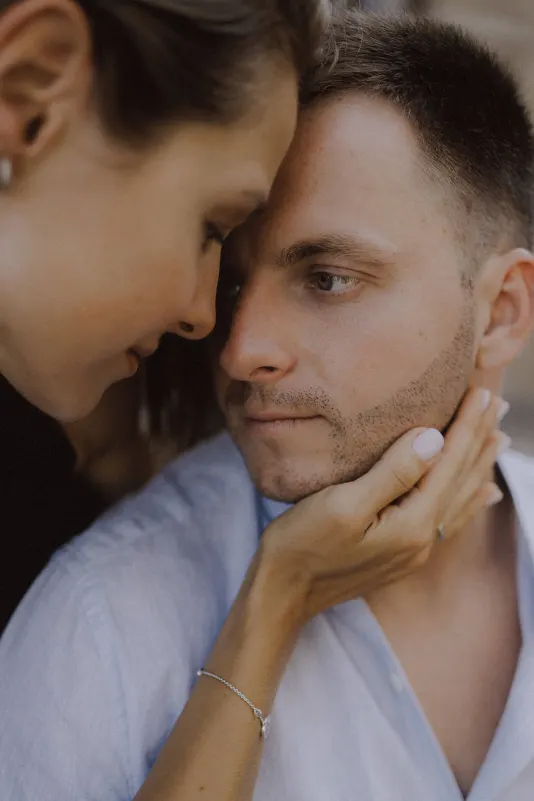 Woman gently holds her partner’s face as they share a quiet, intimate moment during a couples & engagements photoshoot.