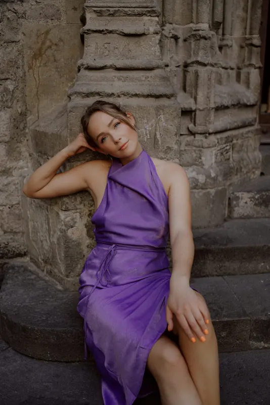 Woman in a purple dress relaxes on stone steps, Vacation Portraits photoshoot capturing a serene city moment.