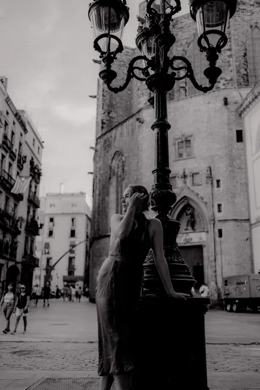 Woman in a summer dress leans on a vintage lamppost, Vacation Portraits photoshoot in a historic European square.