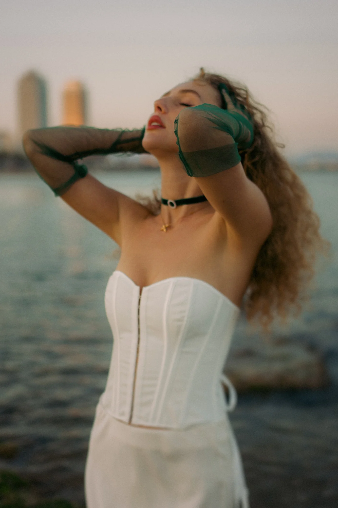 Woman in a white corset dress enjoys a peaceful sunset by the water during a Vacation Portraits photoshoot.