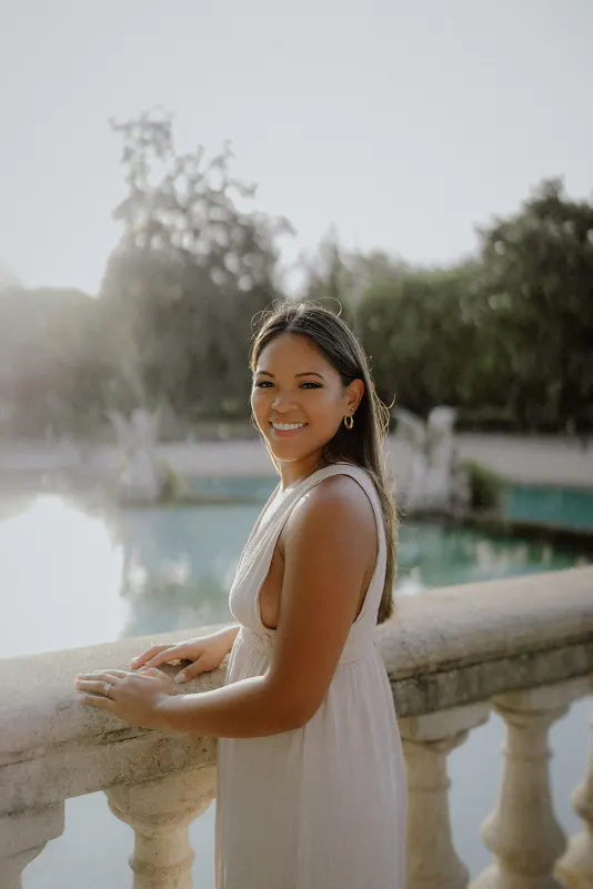 Woman in a white dress smiles by the water at Parc de la Ciutadella during a couples & engagements photoshoot.
