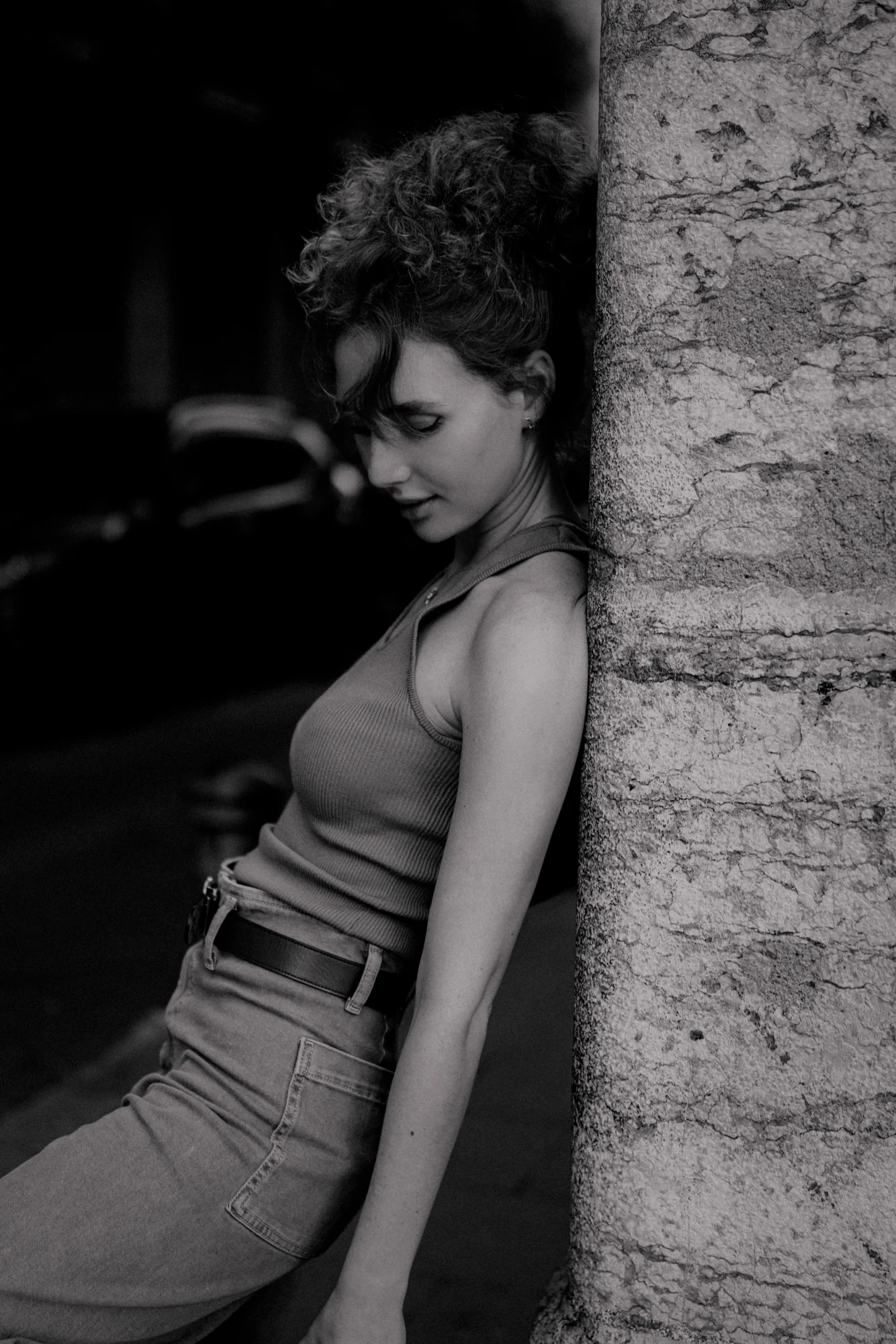 Woman leans thoughtfully against a stone wall during a Vacation Portraits photoshoot, capturing a quiet city moment.