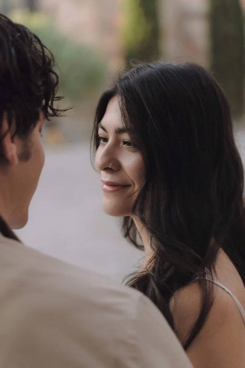 Woman smiling softly at her partner during an outdoor couples & engagements photoshoot, capturing a tender moment.
