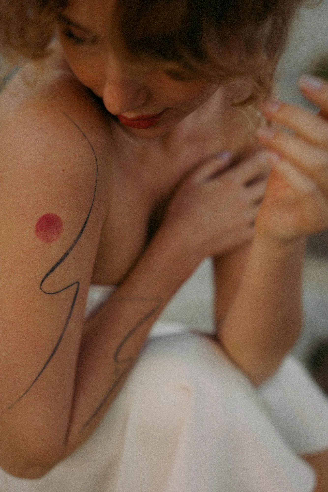 Woman with abstract arm tattoos gazes down softly, captured in an intimate moment during a Vacation Portraits photoshoot.