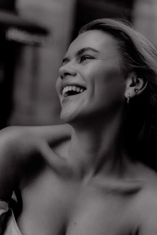 Young woman laughing joyfully during a Vacation Portraits photoshoot, capturing candid happiness in the city.