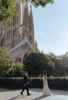 A couple in wedding attire share a romantic moment in front of La Sagrada Familia, perfect for destination photography.