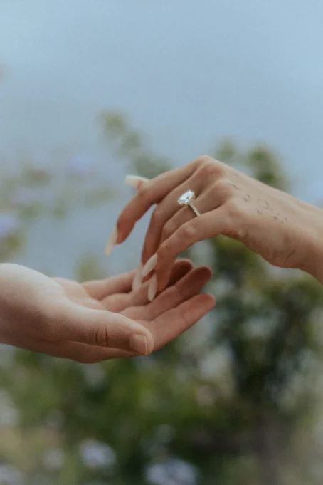 A tender moment as a couple holds hands, engagement ring sparkling at Marimurtra garden.