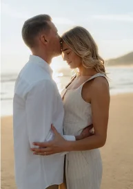 Couple embraces at golden hour on Barceloneta beach, sharing a tender moment during a romantic photoshoot.