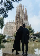 Couple embraces while admiring La Sagrada Familia, captured during a romantic photography session in Barcelona.