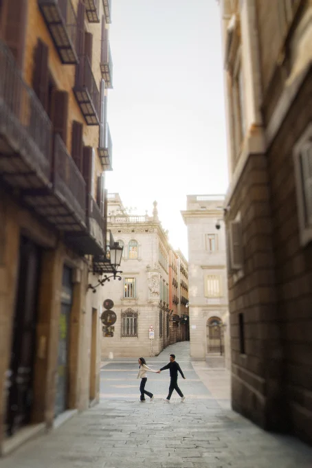 Couple holding hands and laughing while strolling through the charming Gothic quarter, captured by a professional photographe