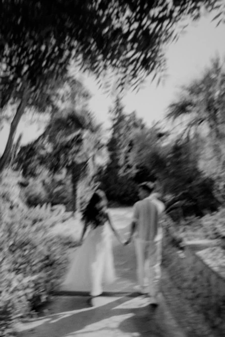 Couple holding hands and walking through Marimurtra garden, captured in a dreamy, romantic photography style.
