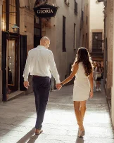 Couple holding hands and walking through sunlit Born area street, perfect for romantic couples photography sessions.