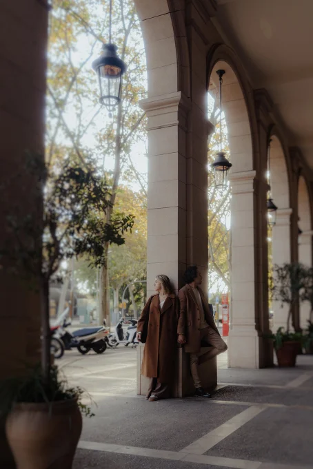 Couple holding hands under elegant arches in Born, sharing a quiet moment during a location photography session.