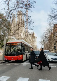 Couple joyfully crossing the street near La Sagrada Familia, Barcelona, captured during a romantic photo session.