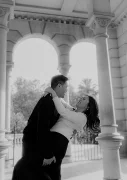 Couple laughing and embracing during an engagement session at Park de la Ciutadella, sunlight streaming through arches.
