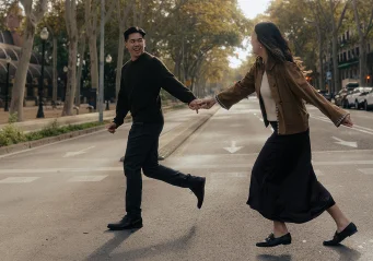 Couple laughing and holding hands while crossing a quiet street in the Born area, captured during a lifestyle photo session.