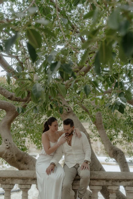 Couple shares a tender moment under lush trees at Park de la Ciutadella, captured during a romantic portrait session.