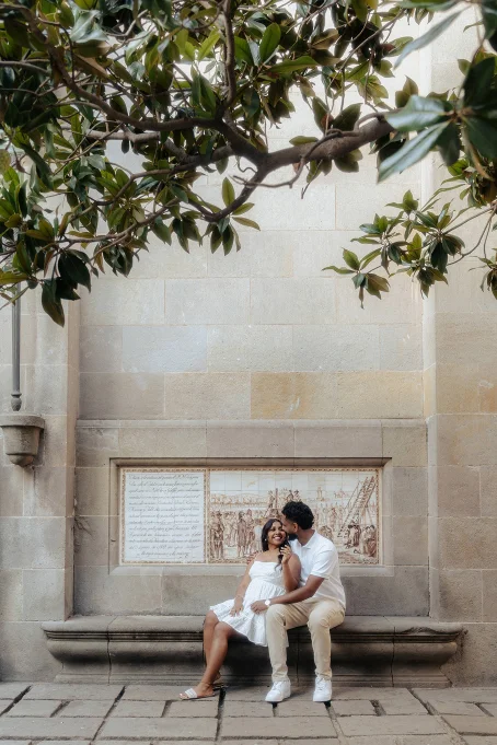 Couple sharing a joyful moment on a stone bench in the Gothic Quarter, perfect for romantic location photography.