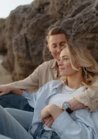 Couple sharing a quiet, intimate moment by the rocks at Ginesta beach, captured during a romantic portrait session.