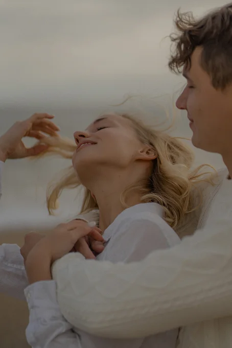 Couple sharing a tender embrace at Barceloneta beach, capturing a joyful moment for a location photography session.