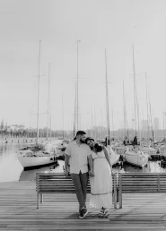 Couple sharing a tender moment on a bench by the yachts at Port Vell, Barceloneta, captured in a romantic portrait session.