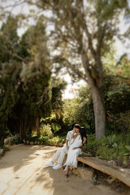 Couple sharing an intimate moment on a bench in Marimurtra garden, captured during a romantic location photoshoot.