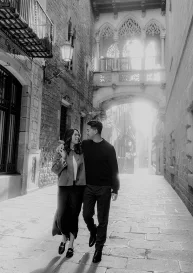 Couple walking arm in arm, smiling in the Gothic Quarter, perfect for engagement photography in Barcelona.