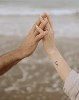 Couple’s hands intertwined by the sea at Barceloneta, capturing intimate engagement photography moments.