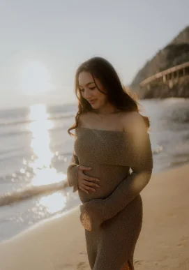 Expectant mother smiling softly at sunset on Ginesta beach, captured during a maternity photography session.