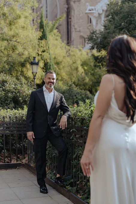 Groom smiles at his bride in elegant attire near La Sagrada Familia, captured during a romantic couple photoshoot.